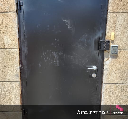 דלת ברזל שחורה מותקנת בקיר אבן חיצוני